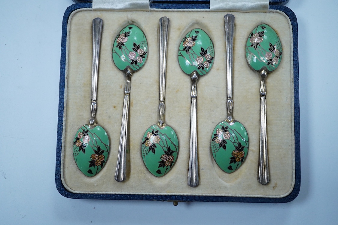 A cased set of six George V Art Deco silver and enamel coffee spoons, By Turner & Simpson, Birmingham, 1933, 98mm, the bowl backs decorated with a rose bush with spider's web.